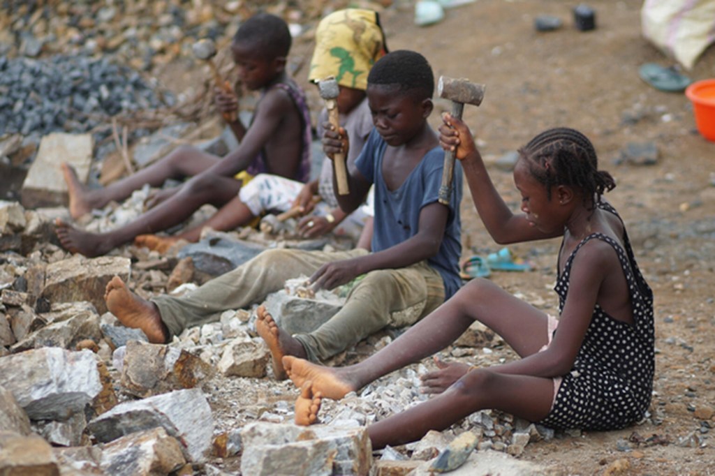 A 12-year-old girl (right) made to work alongside her friends, also children, at a rock quarry in Sierra Leone.